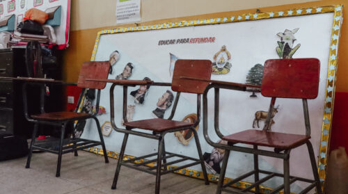 Plastic desks sit empty beneath a banner that reads “Educate to Rebuild.” These silent classrooms mirror the reality of many children in the region who cannot attend school