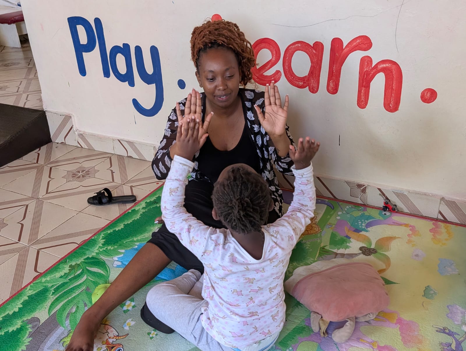 A teacher at Nathan John Learning Centre engaging in one-on-one play with a learner