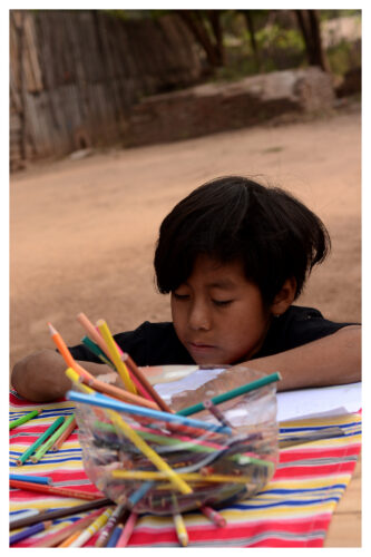 A student works on a drawing in the yard at Matche Ta ïs, where activities often take place outdoors. Photograph by Gabriel Borndones.