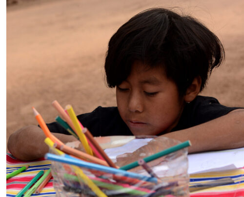 A student works on a drawing in the yard at Matche Ta ïs, where activities often take place outdoors. Photograph by Gabriel Borndones.